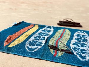 Beach Towel with surfboards on it laying on the sand