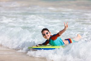 Child on beach surfing on a boogie board