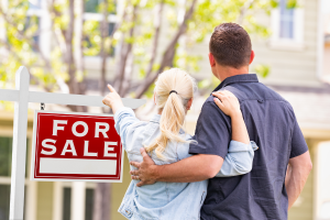 Couple pointing at a house with a for sale sign