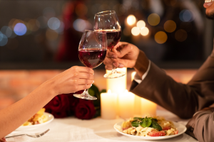 Couple cheers-ing wine glasses at dinner