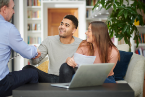 A man and woman sit in a meeting with another man