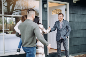 Hre Blog August Buyersmarket couple with a child shaking hands with man outside a house