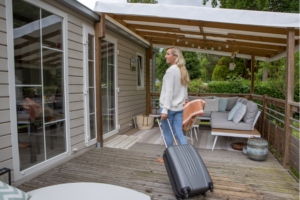 woman with suitcase entering house from porch